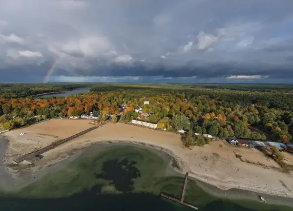 Jesioro Niedzięgiel jesienią, z tęczą na niebie i piaszczystą plażą.