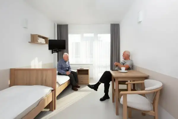 Dwóch starszych panów rozmawia w pokoju sanatorium MSWiA Sopot. Opinie o tym miejscu są pozytywne.