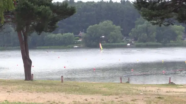Pławniowice jezioro: wiatr napędza żaglówkę, a na brzegu widać piaszczystą plażę i drzewa.