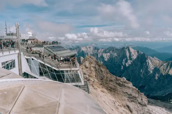 Tłum turystów na tarasie widokowym najwyższego szczytu Niemiec, Zugspitze, podziwia alpejskie krajobrazy.