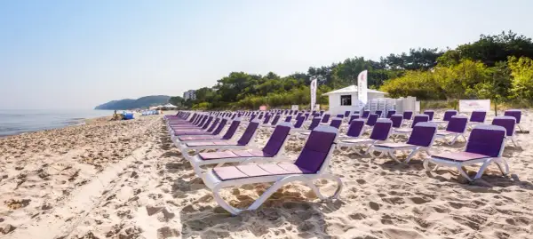 Rzędy leżaków na piaszczystej plaży, idealne na tanie wczasy nad morzem dla 2 osób z wyżywieniem.