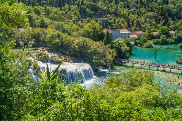 Wodospady Krka w Chorwacji, z turkusową wodą, kaskadami i mostkiem pełnym ludzi.
